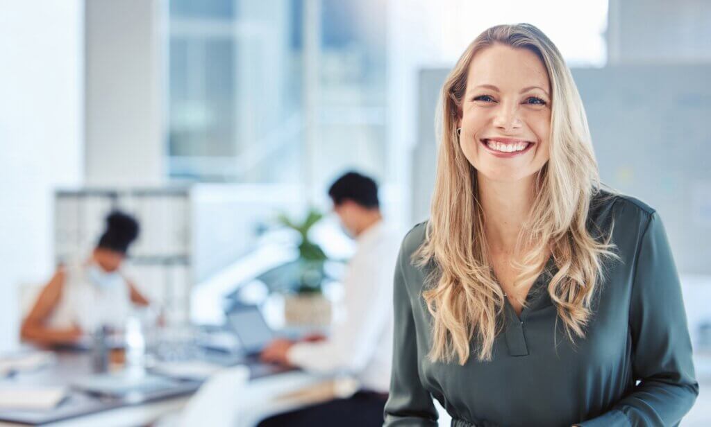 Female leader, manager or CEO with a smile, mission and vision in the office and her team in the ba